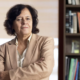 woman in tan suit next to bookcase