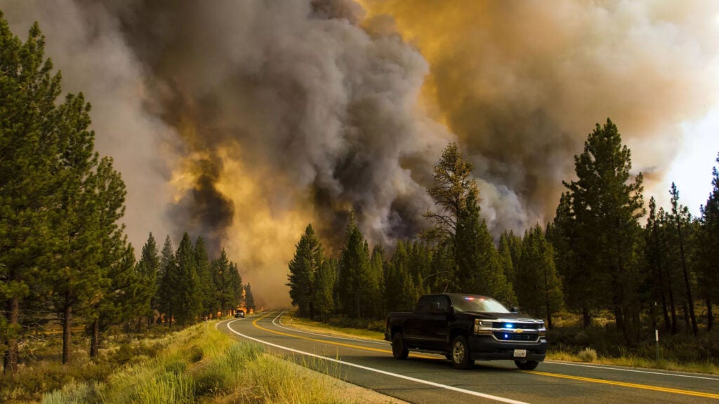 Emergency vehicle on road with flames and smoke visible|||||||woman wearing mask on patio on smoky day||Emergency vehicle on road with flames and smoke visible||
