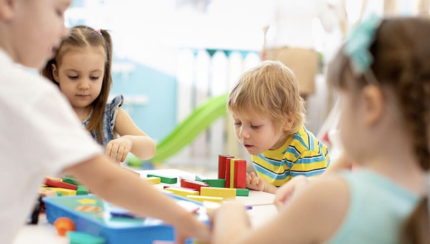 Children at a table, playing with colorful building blocks