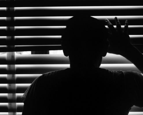 silhoutette of person looking through window blinds