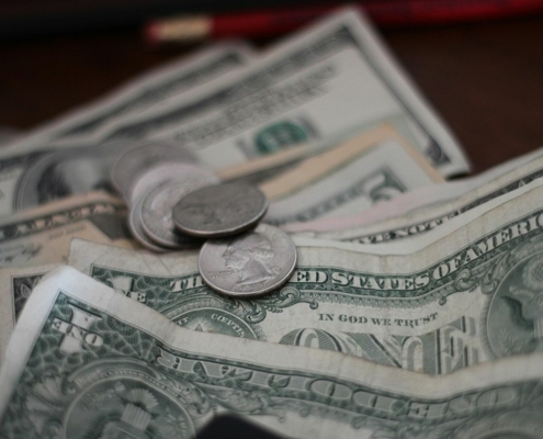 A few coins on top of several one dollar bills