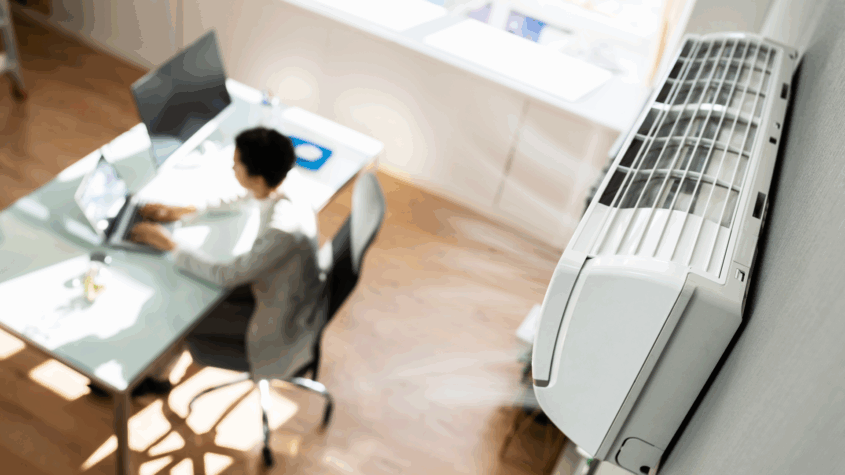 A person working at a desk with a wall mount air conditioner in the frame/