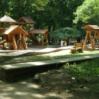 Shady+park+adjusted_hero Shaded playground with wooden play equipment for kids