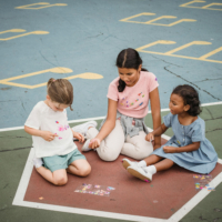 Three young school girls play on the floor during recess