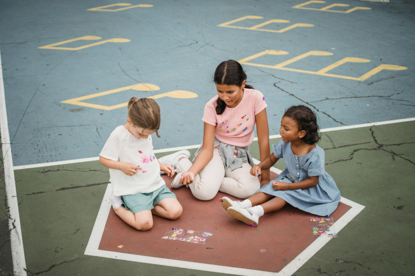 Three young school girls play on the floor during recess