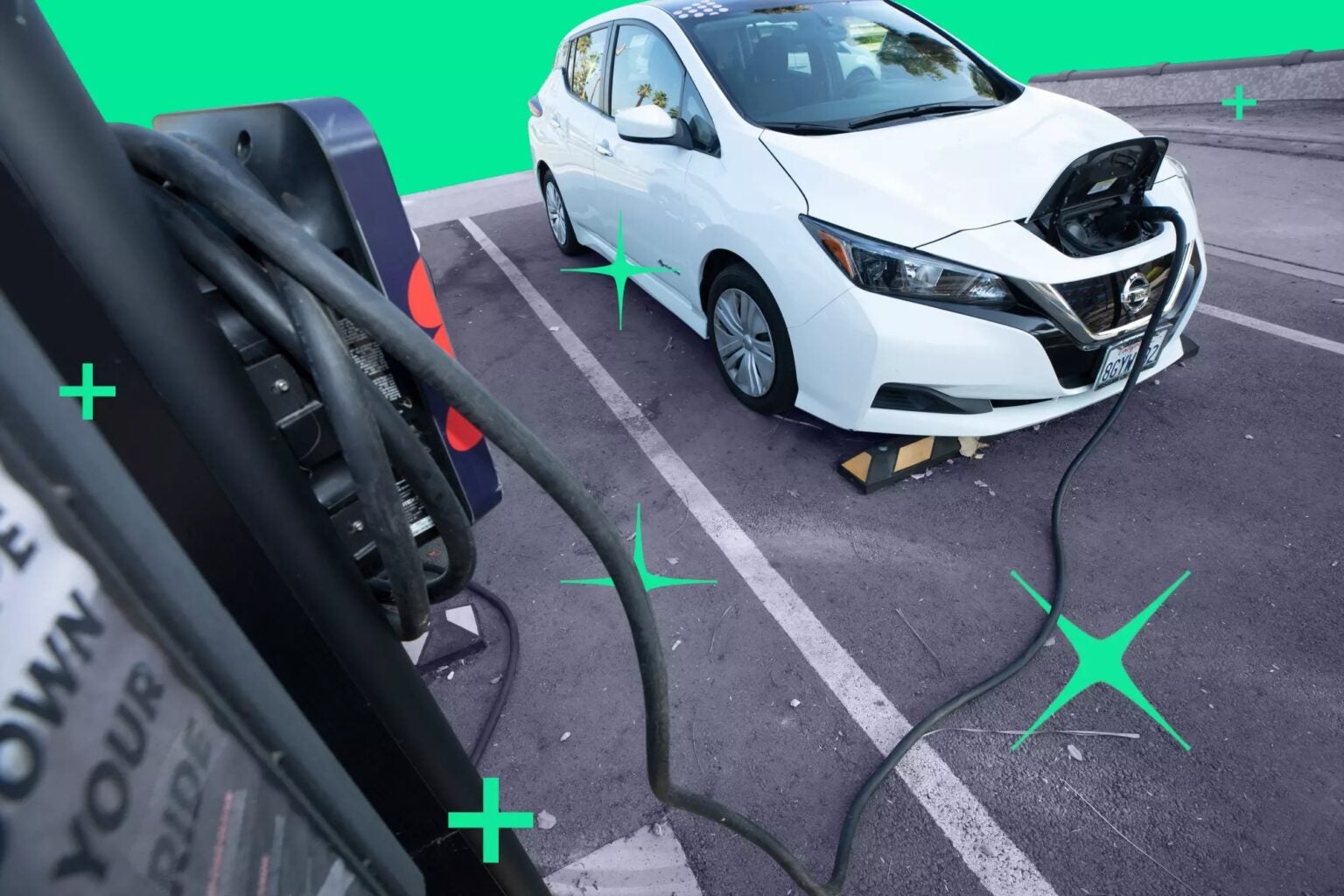 Electric car parked in a parking lot that is plugged in to a charging port
