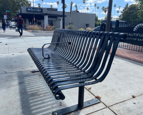 Bus stop steel bench with a metal armrest in the middle to deter people from laying down.