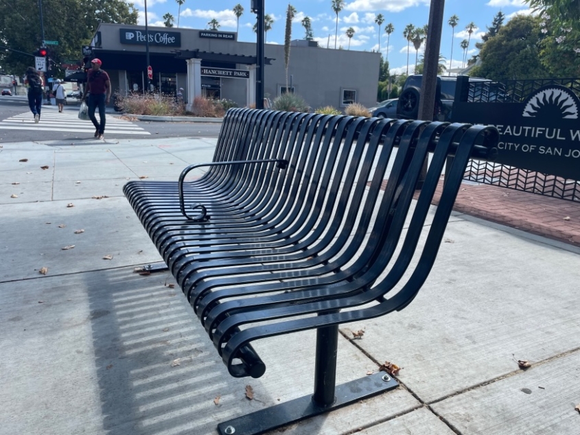 Bus stop steel bench with a metal armrest in the middle to deter people from laying down.