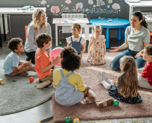 kids in a preschool sitting on the floor in a circle with a teacher