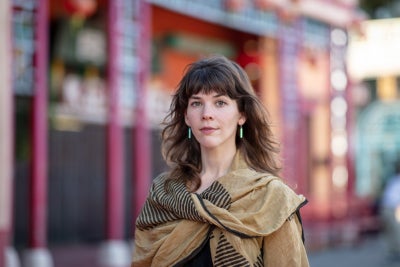 person standing outdoors wearing large scarf