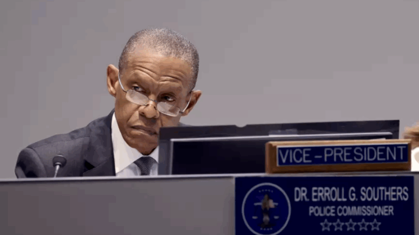 Man in suit and glasses seated at meeting