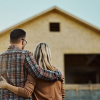 Looking at house Rear view of an embraced couple looking at built structure from outside.