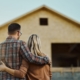 Rear view of an embraced couple looking at built structure from outside.