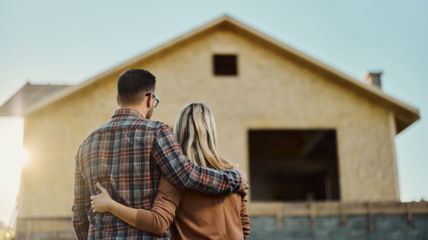Rear view of an embraced couple looking at built structure from outside.