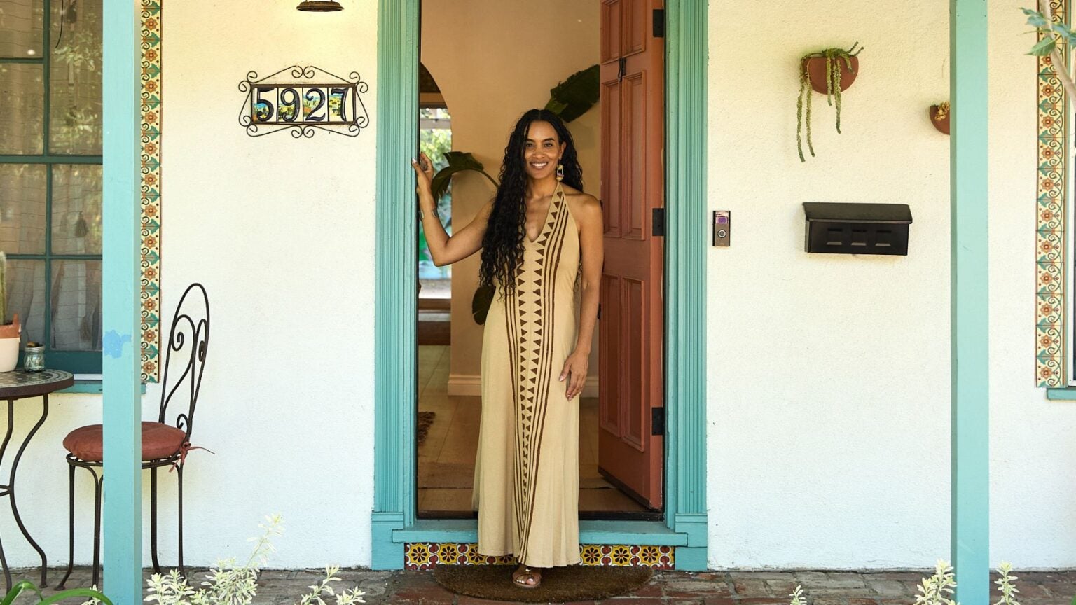 Tamika Lewis stands at the doorway entrance in front of the Women of Color Therapy and Wellness Center|Women sit on the floor in the back garden of WOC Therapy and Wellness center, having a meditation session in the outdoor spaces.|Headshot of Tamika Lewis MSW Alumna