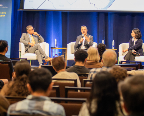 3 panelists speak in front of an audience on stage.