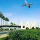 Photo of LAX sign with an airplane flying overhead at the los angeles airport.