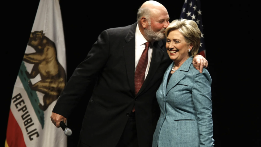 Man in suit embraces woman in suit on stage