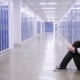 boy sitting with head in hands in school corridor amid blue lockers