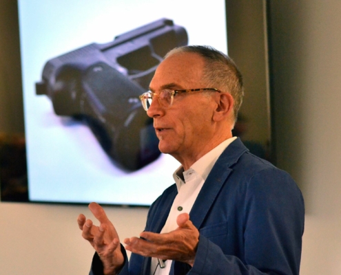Professor Mark Kaplan speaks in class about firearm suicides and behind him is an image of a gun on the projector.