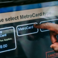 Hand typing on a metrocard machine at a new york subway to pay for a fare.