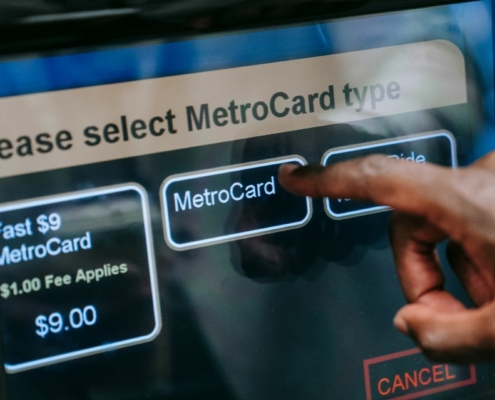 Hand typing on a metrocard machine at a new york subway to pay for a fare.