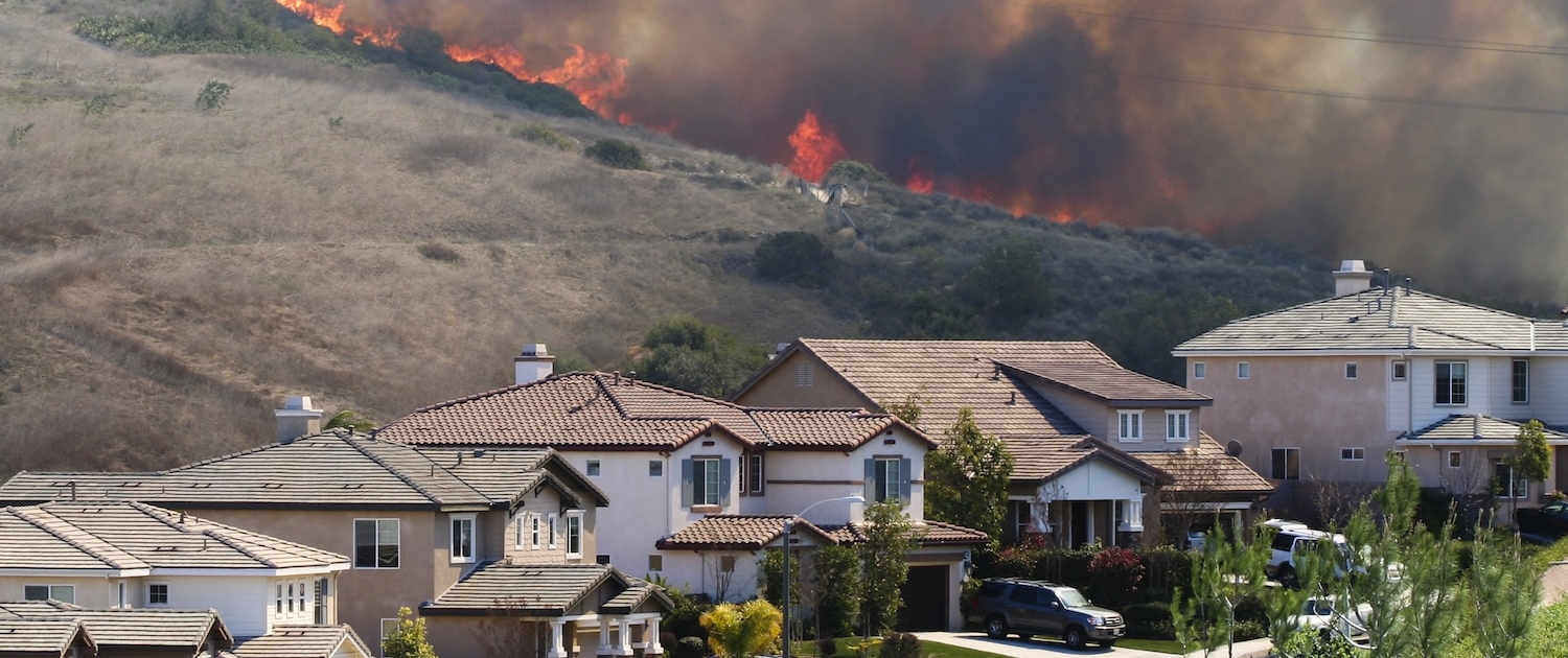 Flames on ridge in back of street with two-story houses