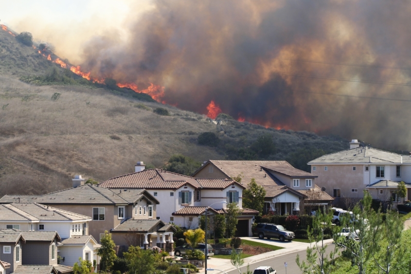 Flames on ridge in back of street with two-story houses