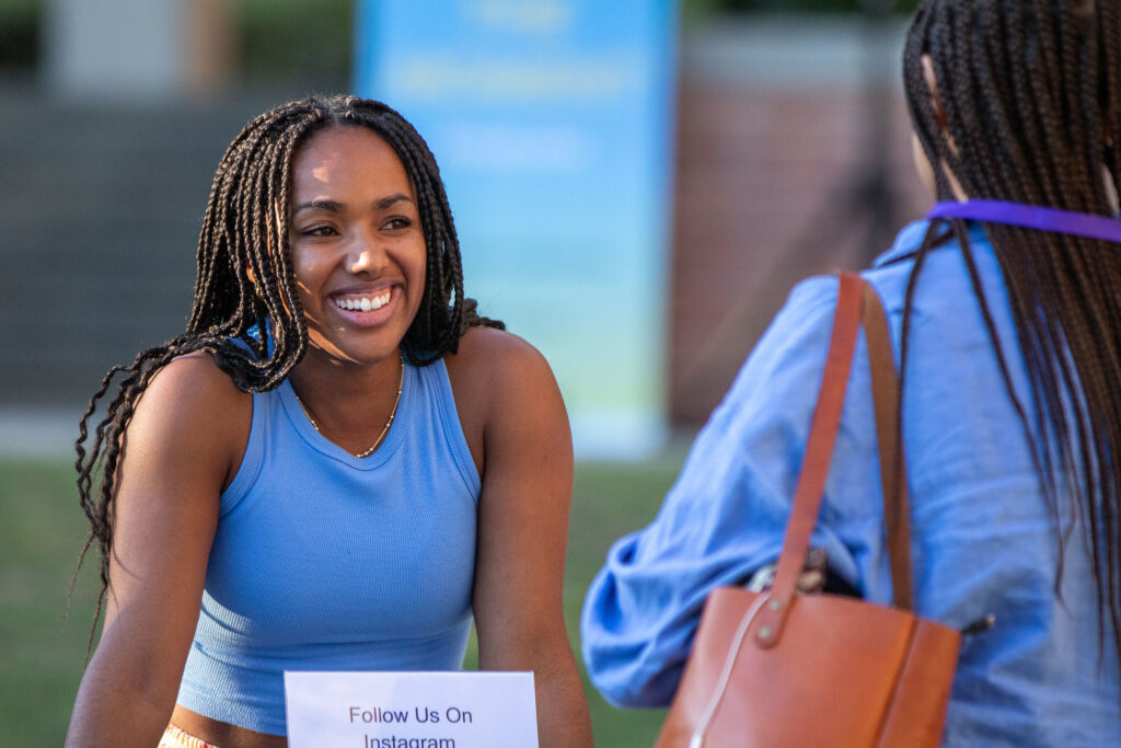 Woman wearing a blue tank top smiles at a friend at the Luskin Block Party