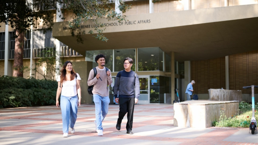 Photo of three students walking in front of the UCLA Luskin School of Public Affairs building.