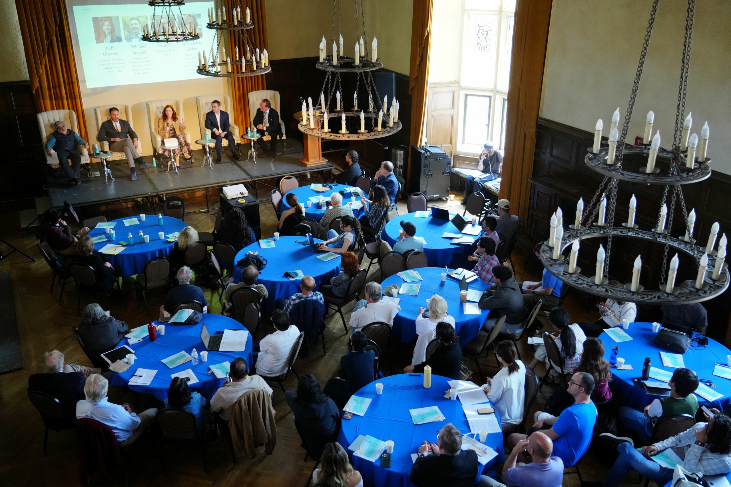 Aerial shot of the attendees seated in round tables and panelists on stage at the  UCLA Kerckoff Grand Salon for the May 6 event with the Berggruen Governance Index.