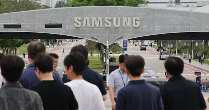 a crow od people walk below a Samsung sign.