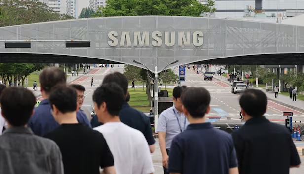 a crow od people walk below a Samsung sign.