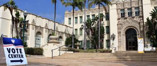 Vote center sign in front of ornate building and palm trees