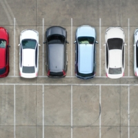 Aerial view of a parking lot with a row of cars and another row of empty parking spaces.