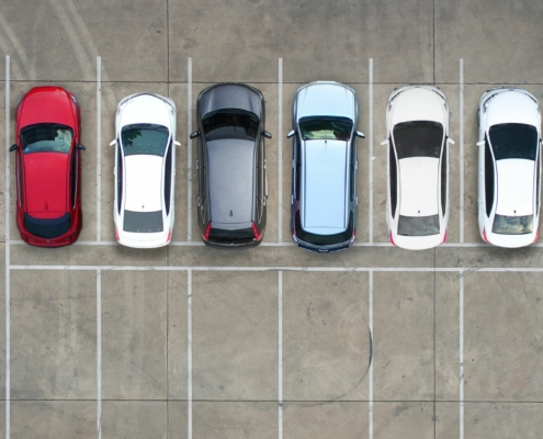 Aerial view of a parking lot with a row of cars and another row of empty parking spaces.