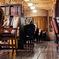 The venue features a cozy, rustic aesthetic with book-filled shelves serving as dividers between seating area