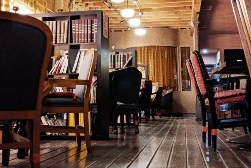 The venue features a cozy, rustic aesthetic with book-filled shelves serving as dividers between seating area