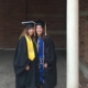 MSW Alumni Emily Dillon graduate of 2016 class, stands with her female friend, both are in cap and gown at UCLA graduation in front of a brick building.