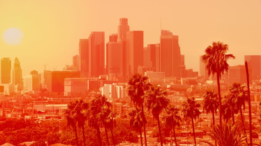 Photo of Los Angeles downtown with palm trees on an extremely hot day, the photo is in a bright orange filter to indicate heat levels