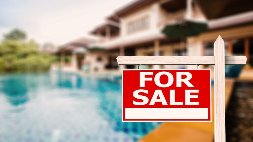 Backyard of a house with a swimming pool with "For Sale" sign