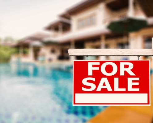 Backyard of a house with a swimming pool with "For Sale" sign