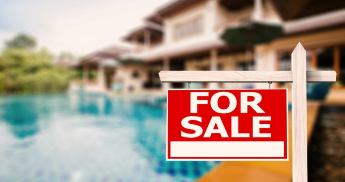 Backyard of a house with a swimming pool with "For Sale" sign