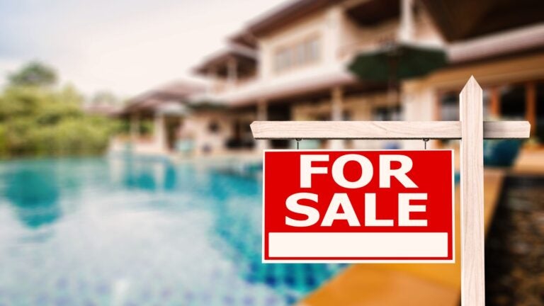 Backyard of a house with a swimming pool with "For Sale" sign