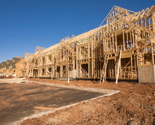 a complex of buildines in process of getting built, framing is done and some sheathing sitting on a muddy construction site.