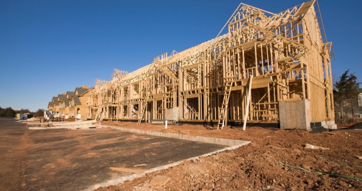 a complex of buildines in process of getting built, framing is done and some sheathing sitting on a muddy construction site.