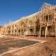 a complex of buildines in process of getting built, framing is done and some sheathing sitting on a muddy construction site.