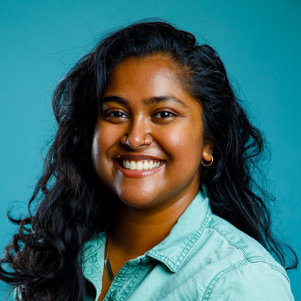 headshot of person with dark hair against teal background