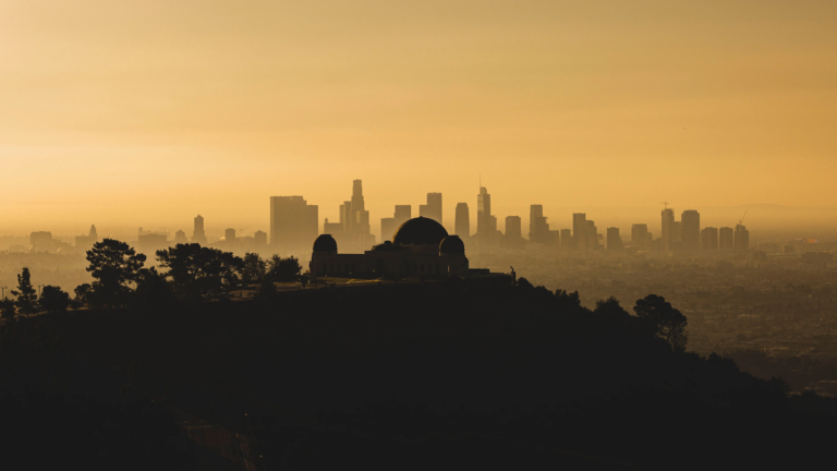 silhouette of Griffith Observatory set again orange sky and Los Angeles skyline