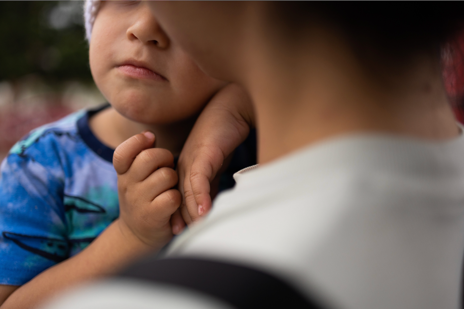 young child with face only partially shown held by adult